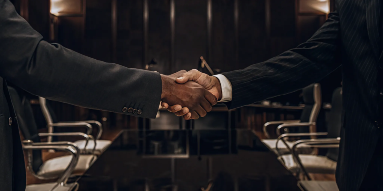 A small business owner shaking hands with an invoice factoring company representative.