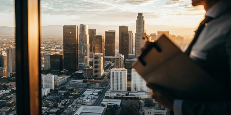 Businessperson overlooking Los Angeles, planning how to get funding to fulfill large orders.